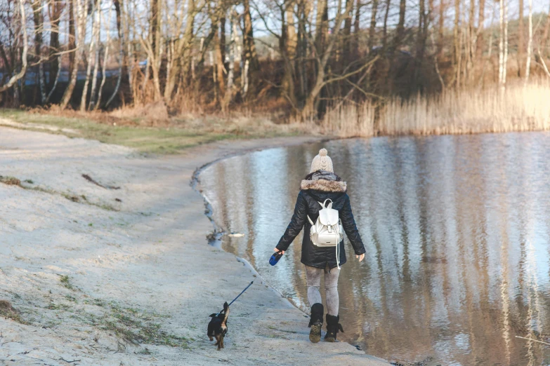 a woman walking her dog on a sandy path