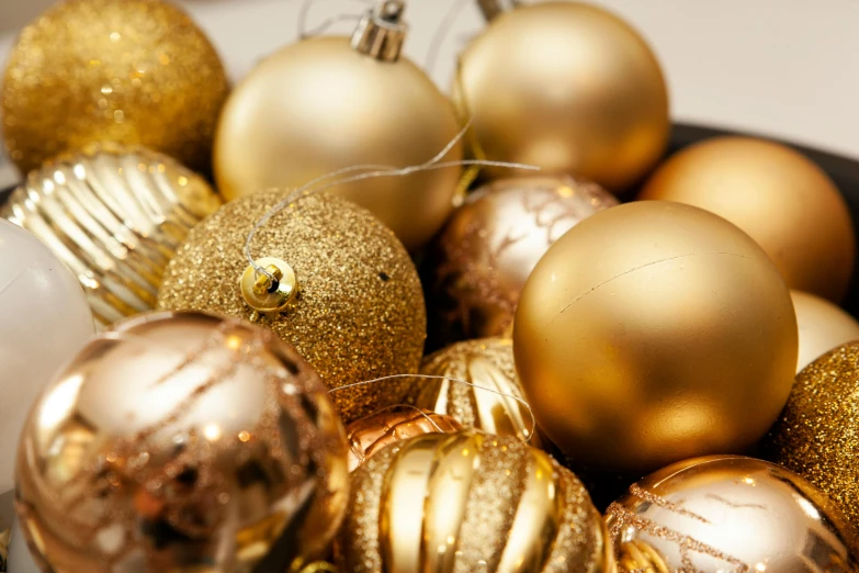 an assortment of gold and silver christmas ornament in a display bowl