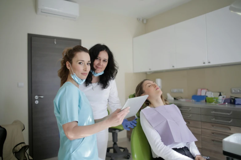 three women smiling and looking at the camera in a dental office