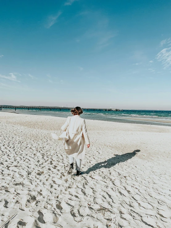 the person is walking along the beach towards the water