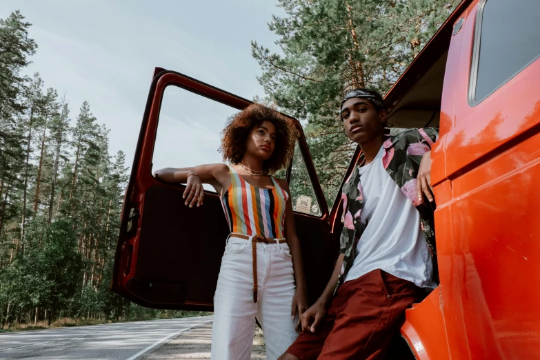 two people in white pants and striped top stand by the back of an old red truck