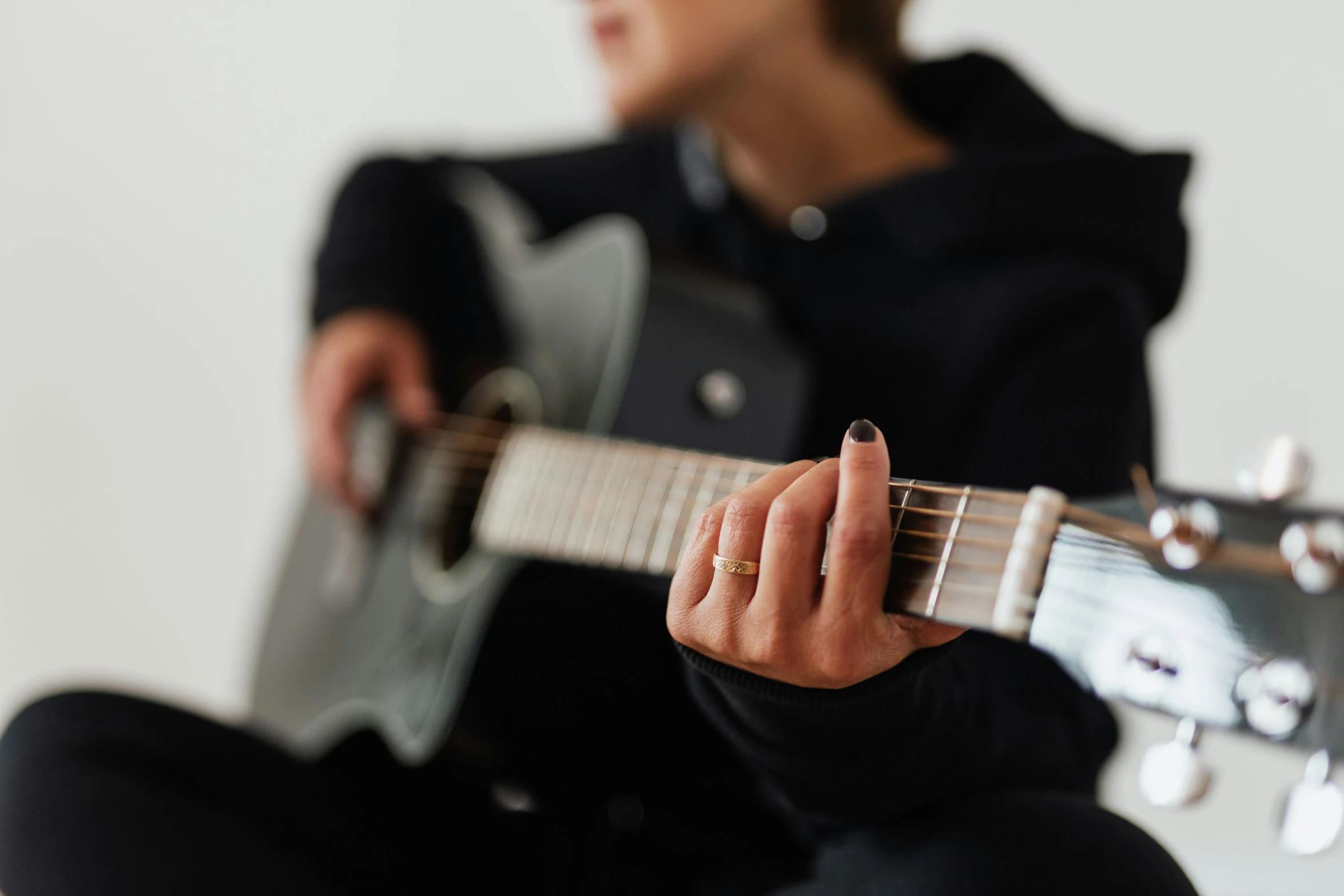 a woman with short nails playing an acoustic guitar