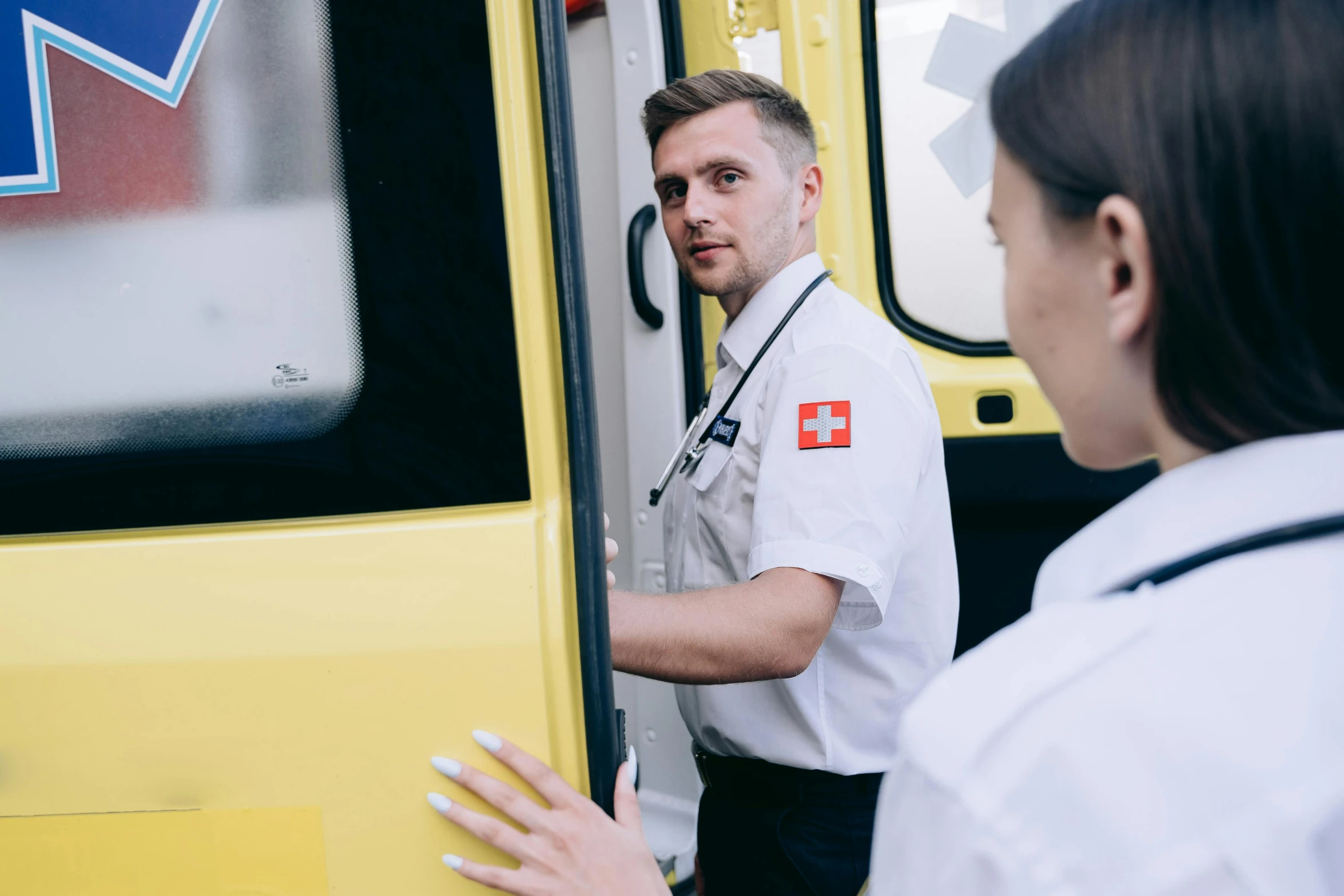 a man standing next to a woman who is standing in front of a yellow vehicle