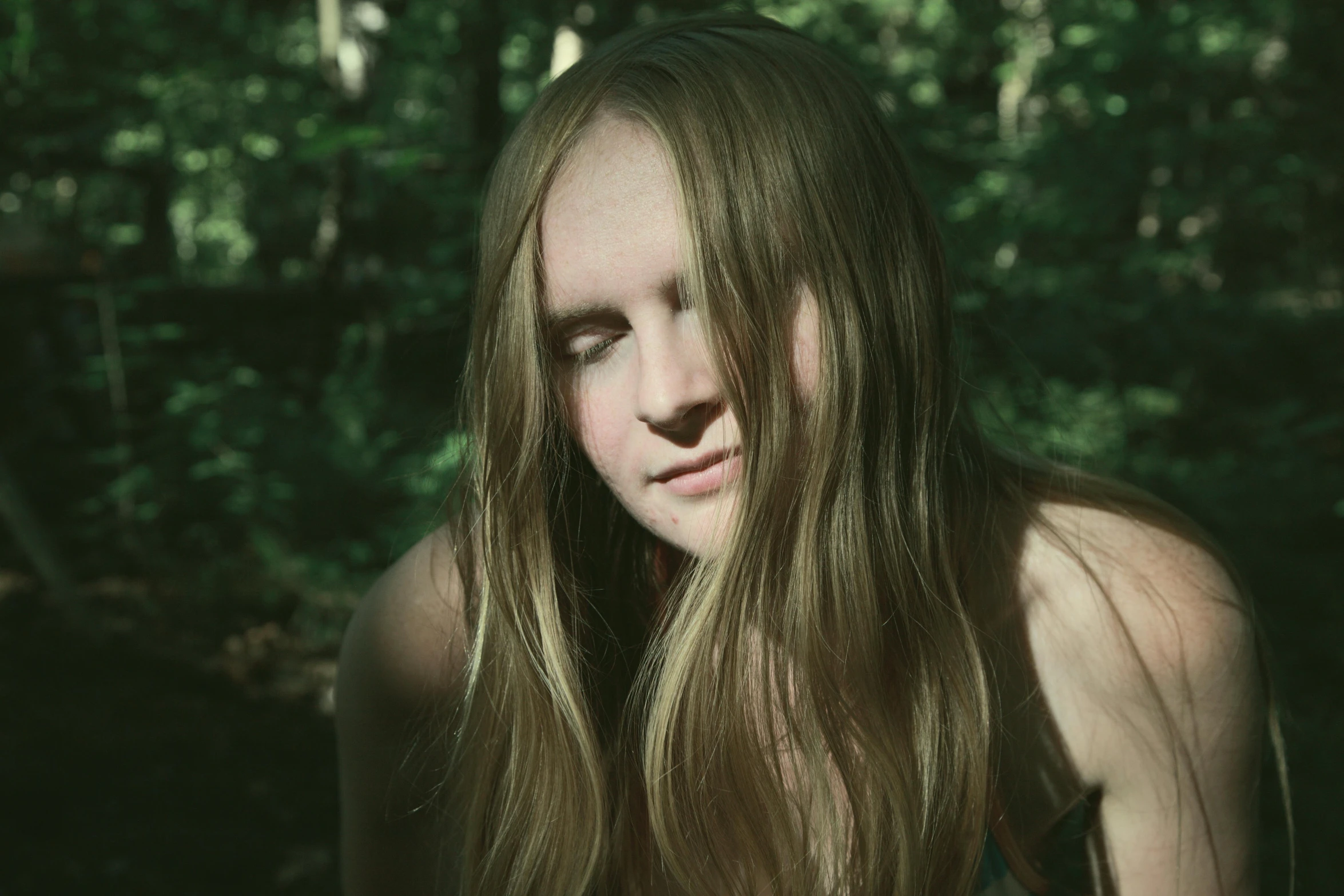 a woman with long brown hair standing in the woods