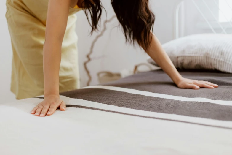 a person bending over to put a mattress on top of it