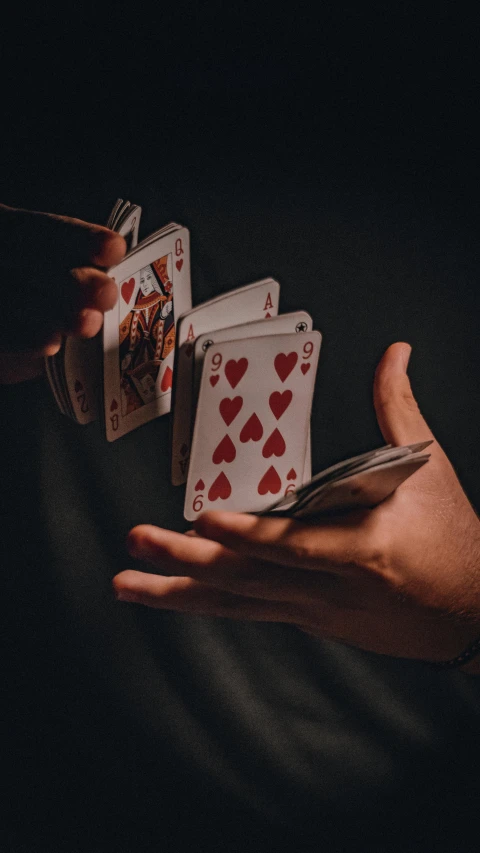 a person holds four playing cards and a knife