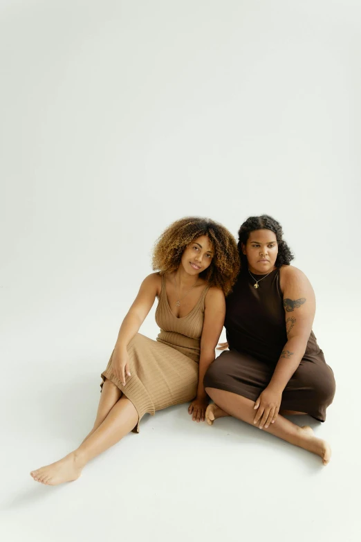 two woman sitting on the floor posing for a po