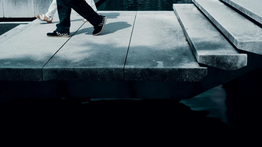 a man in jeans and white shirt walking on cement walkway