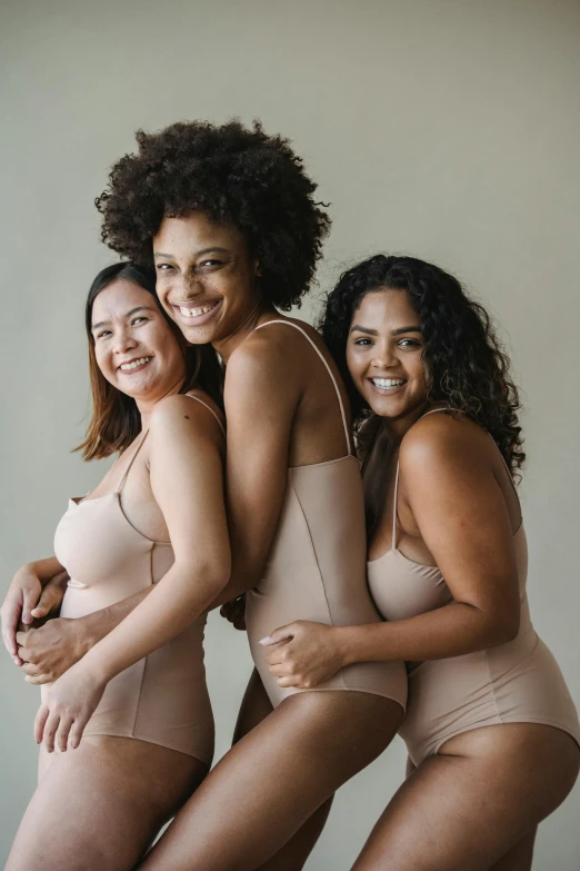 three women in bodysuits pose for a picture together