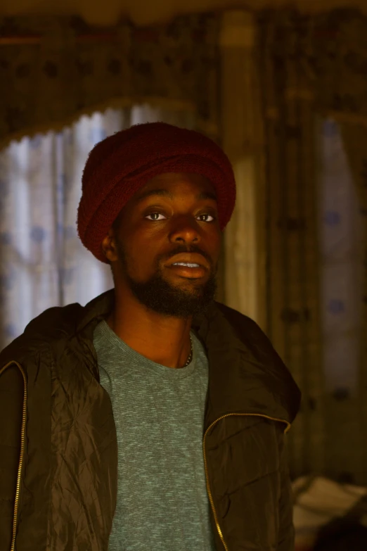 a young man wearing a red hat in front of a window