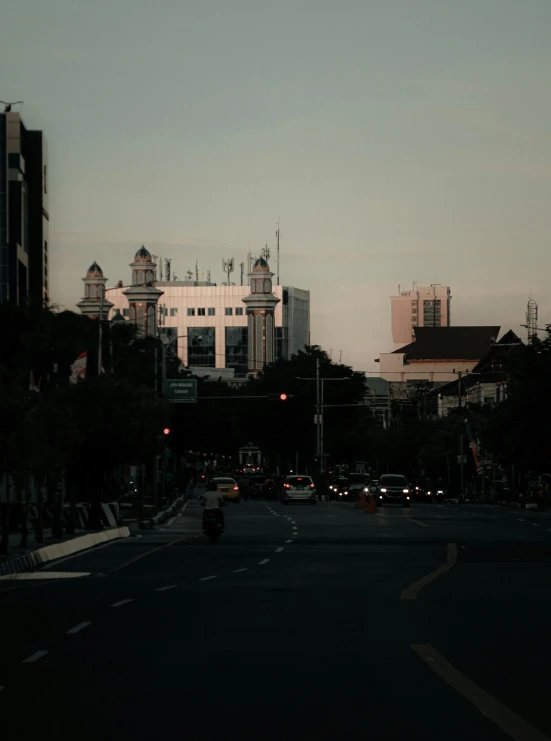 cars on an empty street with buildings and lights behind them