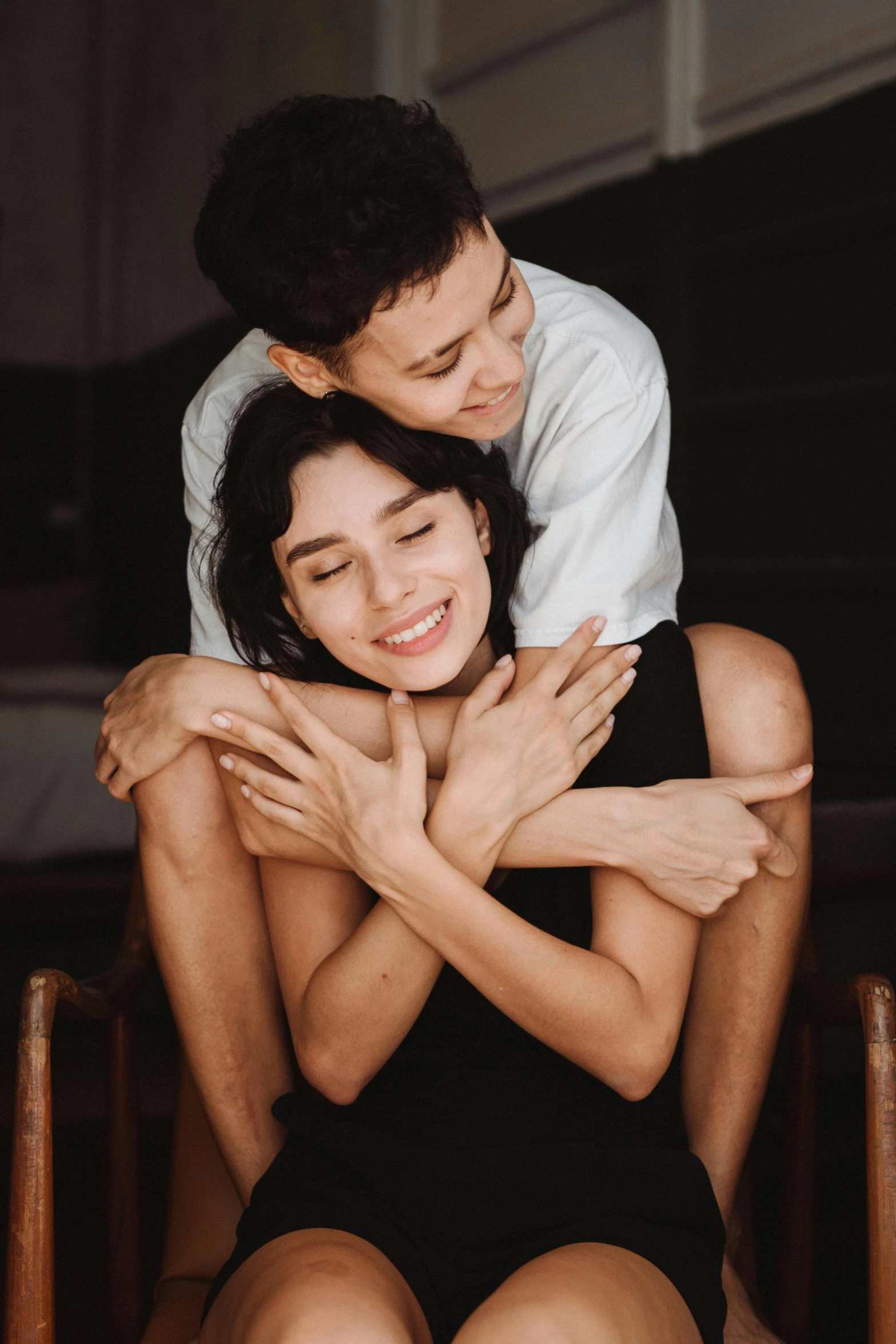 the young man is sitting on top of the woman and hugging her back