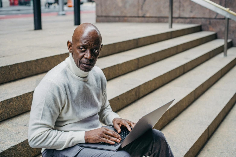 a man with an open laptop on some steps