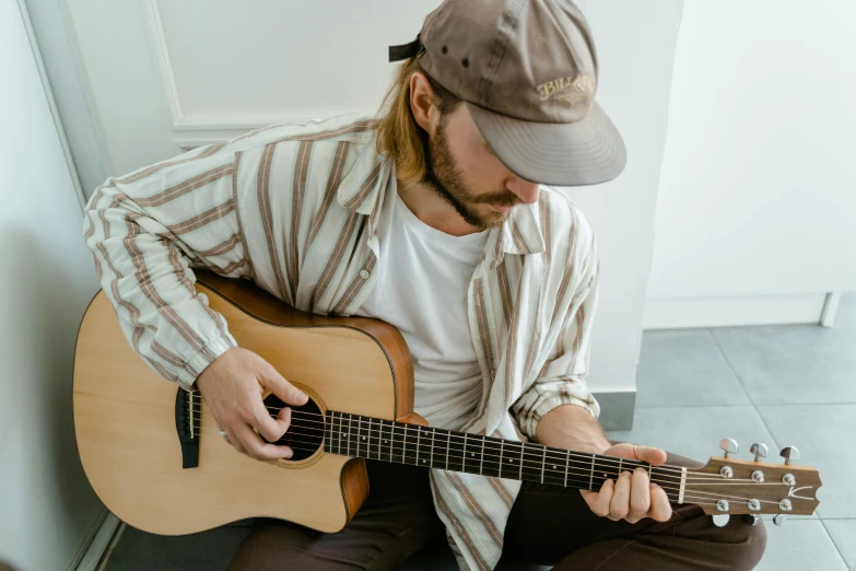 a man wearing a hat plays the guitar