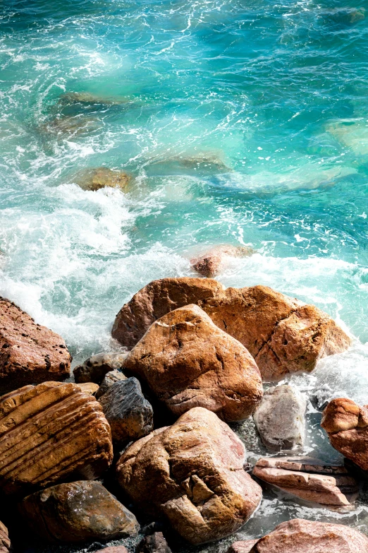 a view of water from the top of rocks in the beach