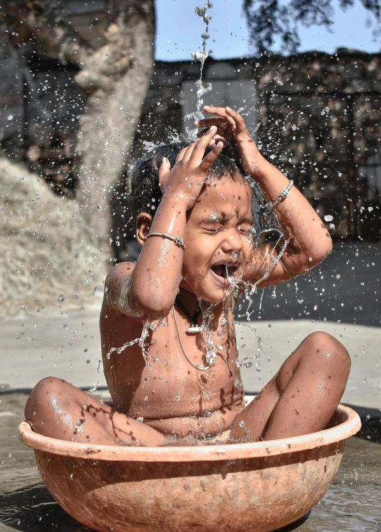 a boy is sitting in the fountain and playing