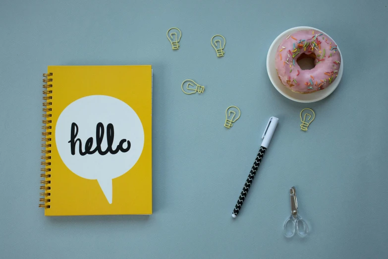 a notebook with a message bubble on it sitting next to a donut