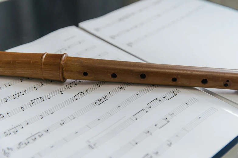 wooden recorder sitting on music sheet next to musical notes
