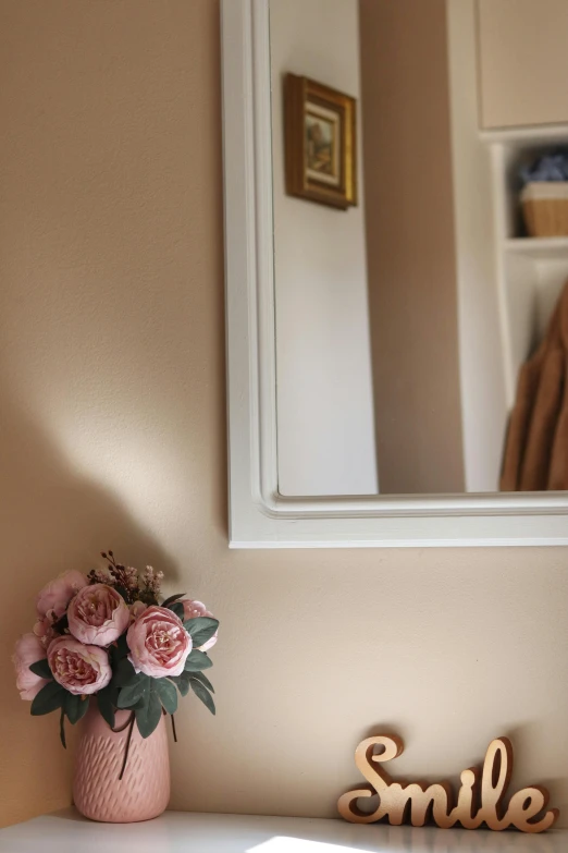 small pink flowers in a pink vase beside the mirror