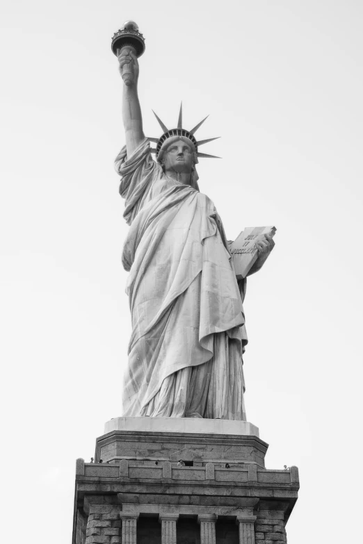 the statue of liberty sits in front of a grey sky