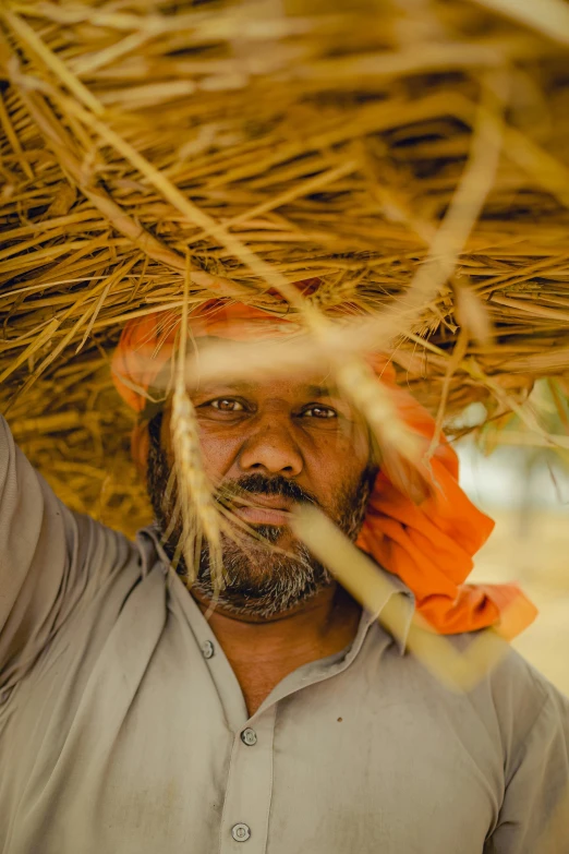 a man wearing an orange hat and a straw umbrella