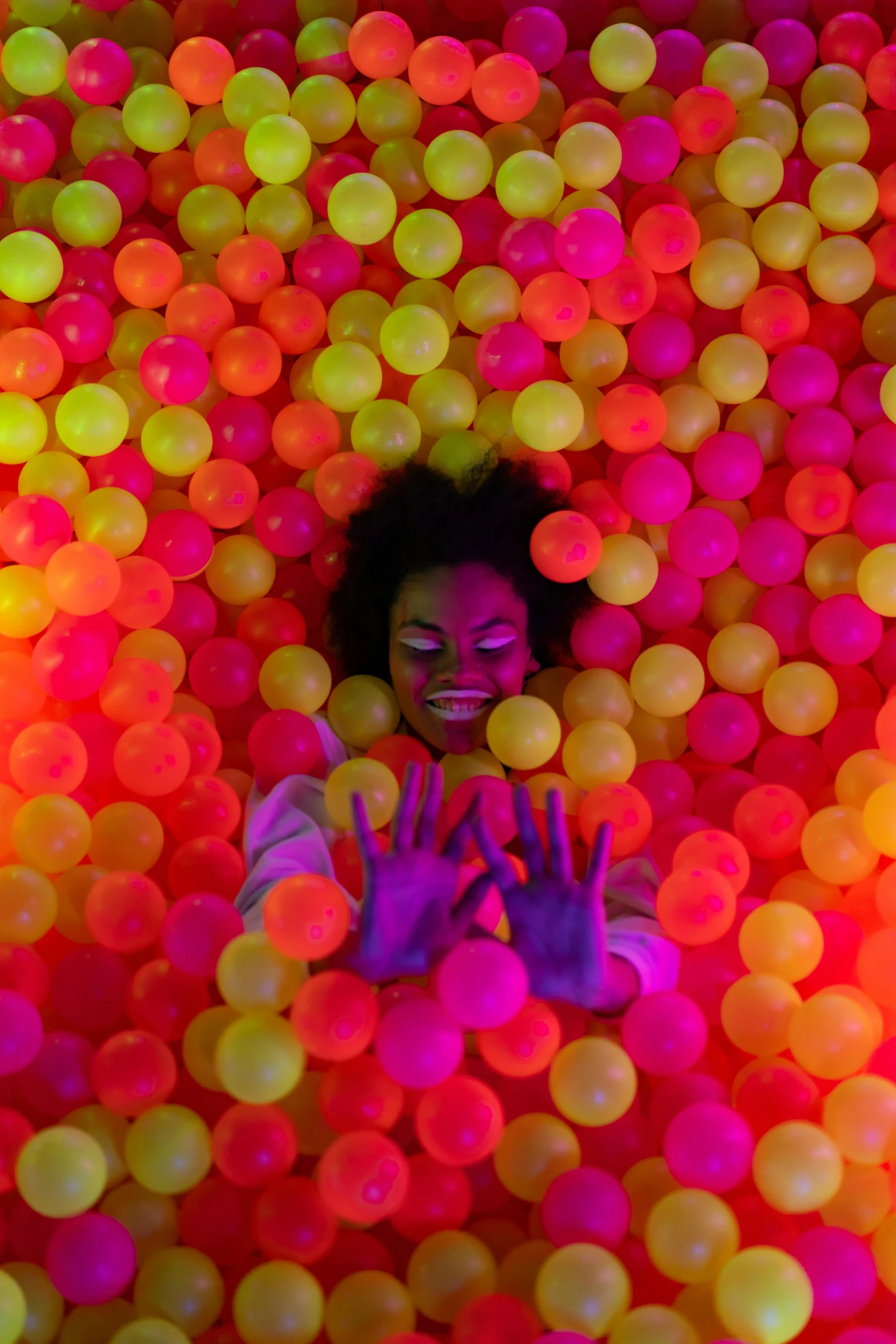 woman is surrounded by colored balls in front of her face