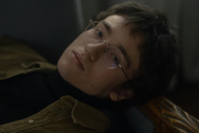 a man laying on top of a chair wearing glasses