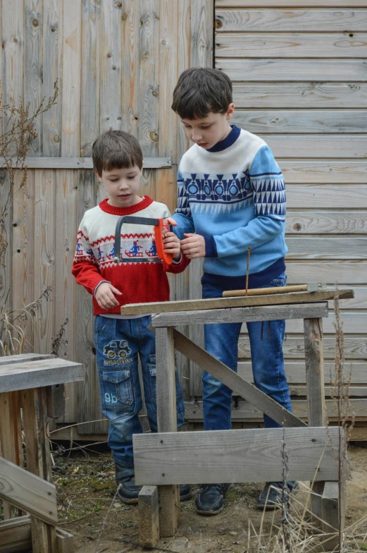 two boys in sweaters standing on the bench