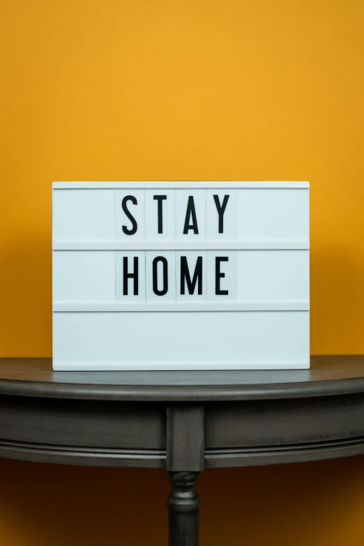 a sign that reads stay home sits on top of a desk