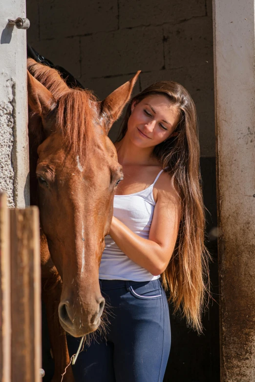 a woman with her hand on the nose of a brown horse