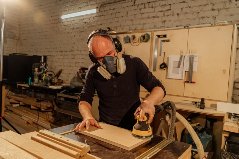 a man is sanding with a sander in a workshop