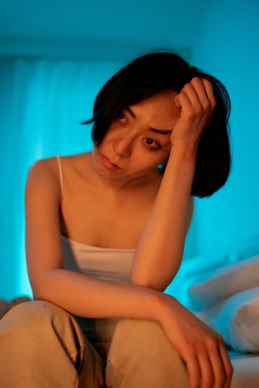 an asian woman sits in bed and stares at the camera