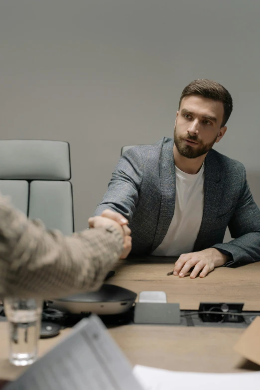 a man shaking hands with another man across the table