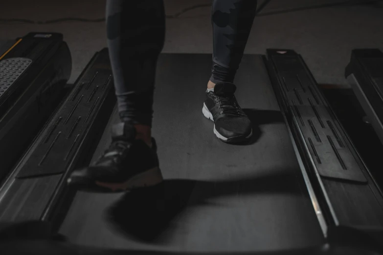 the person is walking on the tread while wearing a black and white shirt