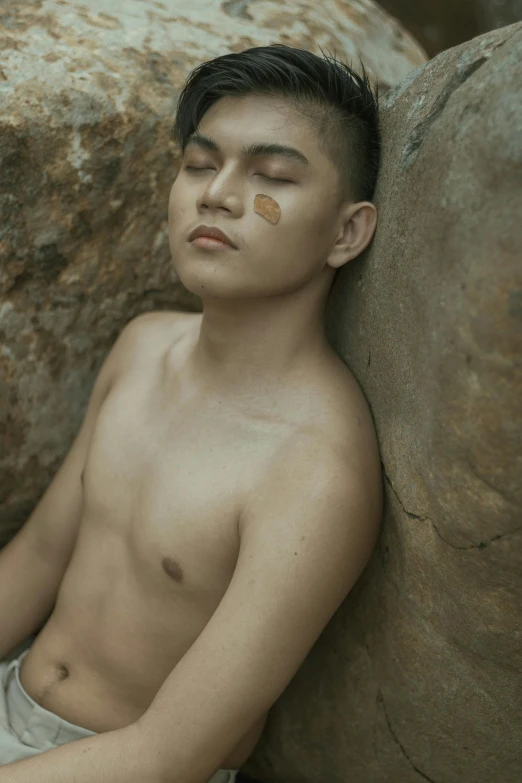 a man resting on a rock looking to his left