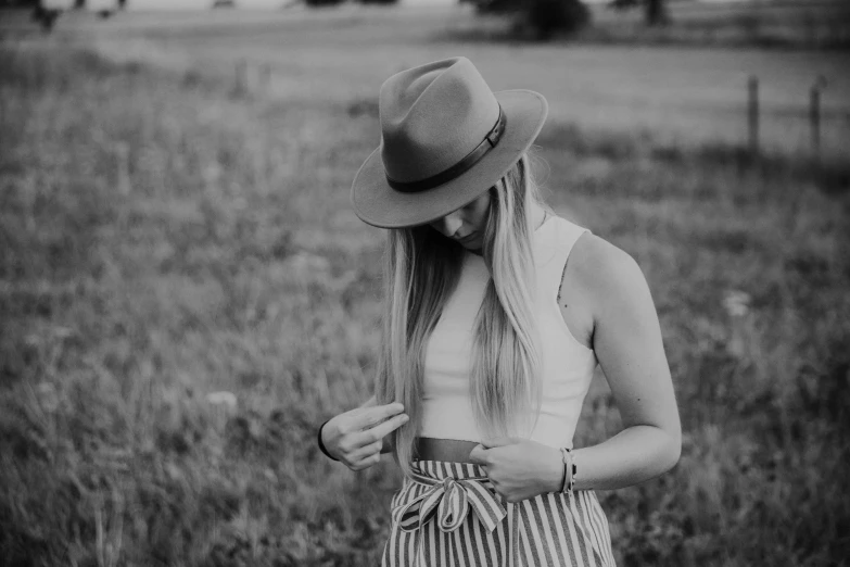 a woman wearing a hat standing in a field