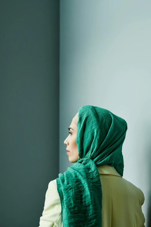 a person in a green shawl stands back towards the camera