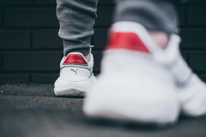 the feet of a person standing near a brick wall