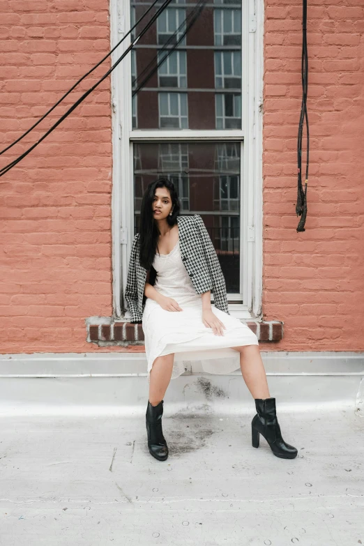 a woman in a dress and coat is sitting on the bench