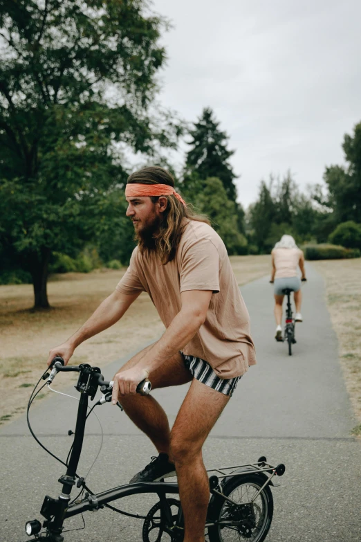 a bearded man riding his bicycle down a paved road