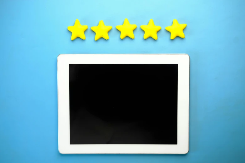 a tablet sitting on top of a blue counter next to five stars