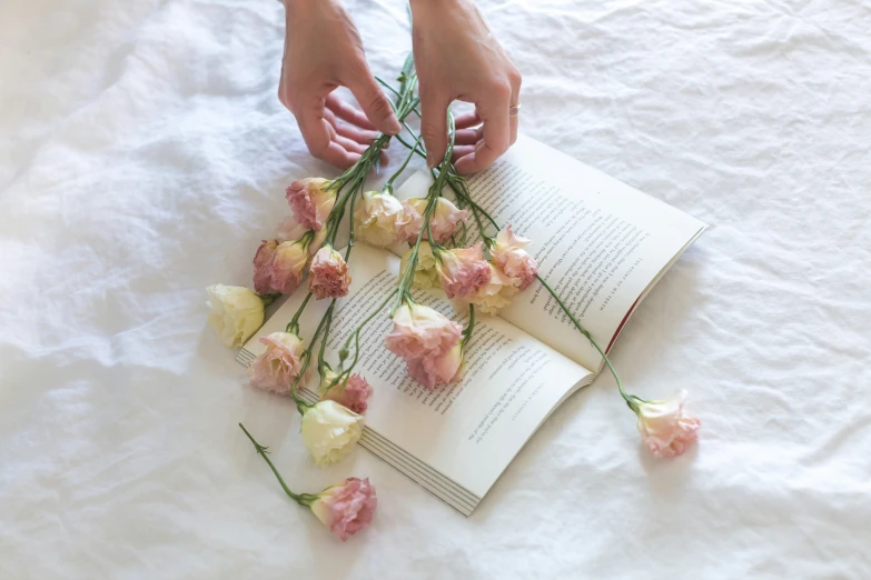 a person that is grabbing some flowers by a book