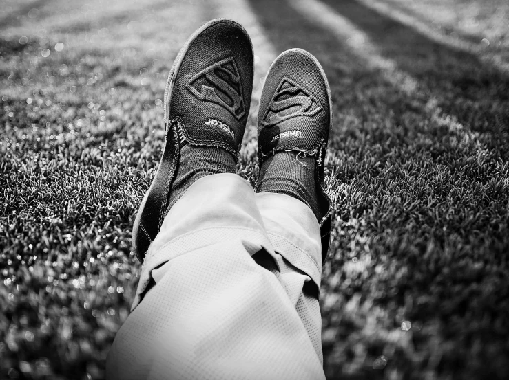 the person is lying on the grass on his feet