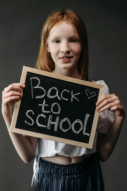 a little girl holding up a back to school chalk board