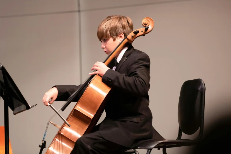 a child in black suit playing a cello