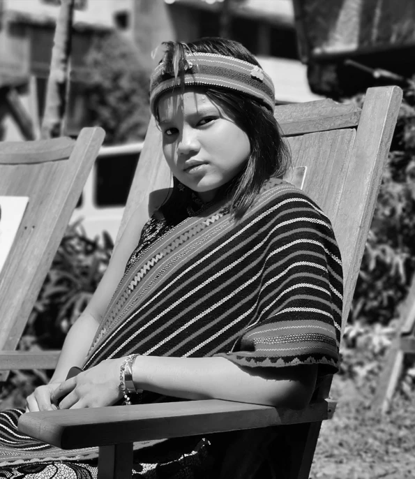 a black and white image of a woman sitting on a lawn chair