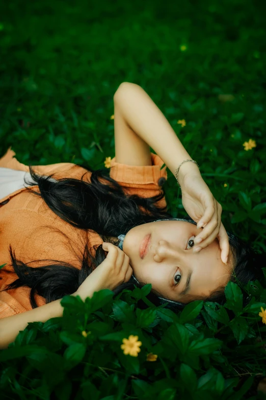 a woman laying in the grass next to green plants