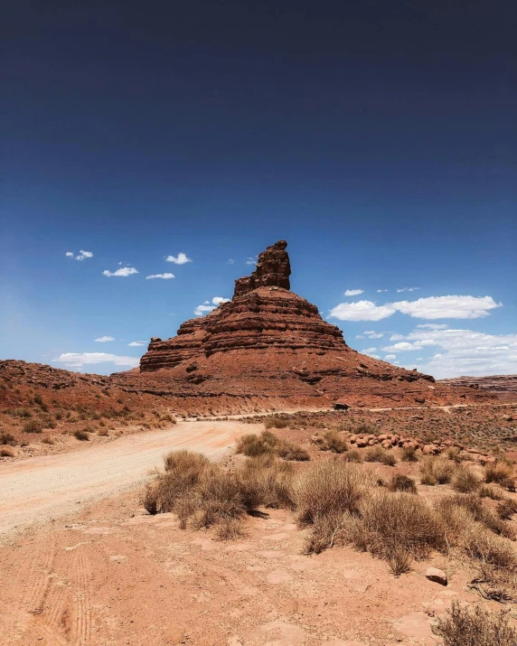 a desert area has red cliffs and a small road