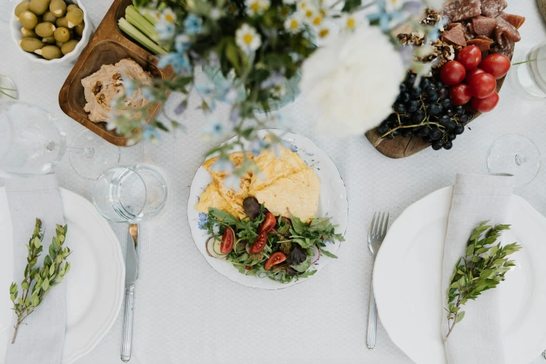 a table setting has white place mats with place settings and flowers on them