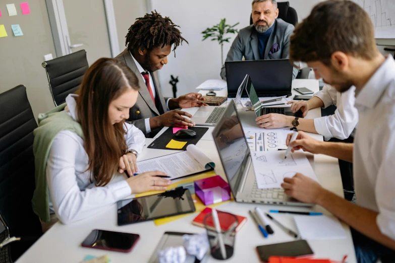 a group of people sitting at a table with their laptops